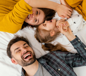 Imagen de una familia tumbados en la cama